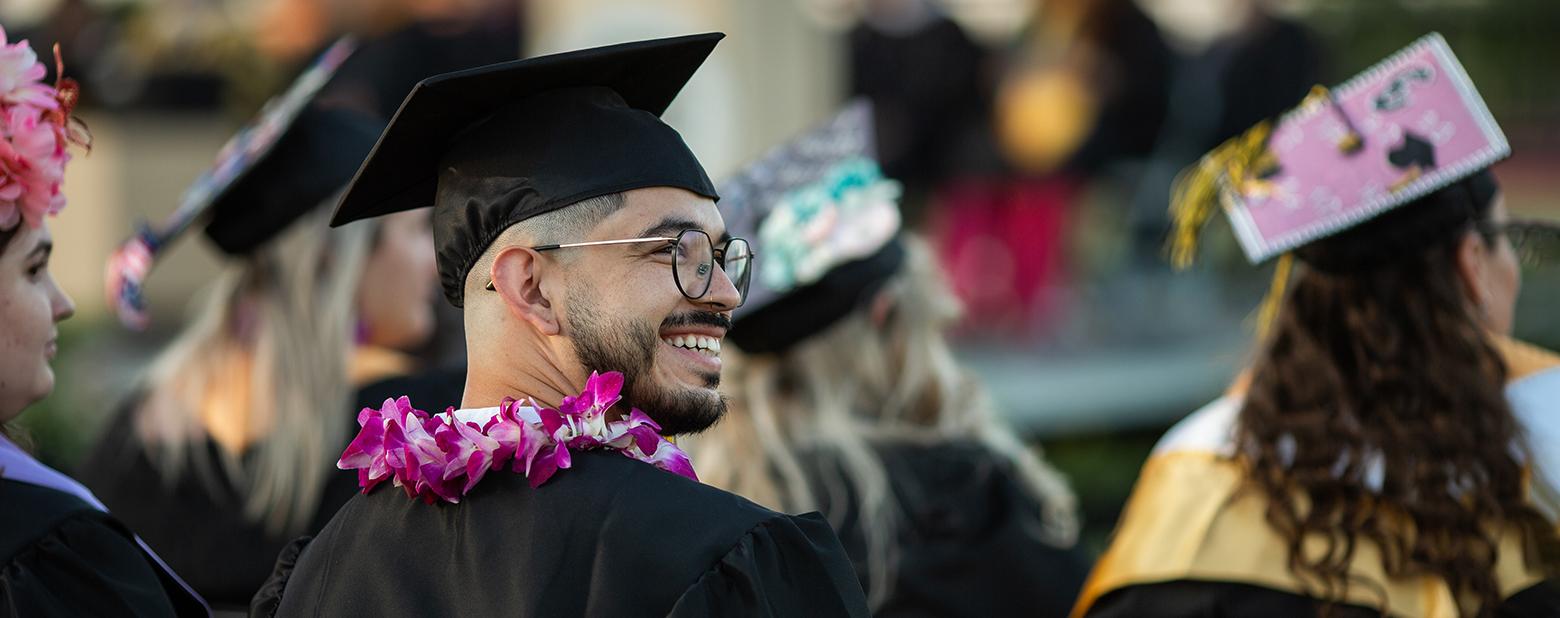 照片中，一名新濠新天地的毕业生戴着学士帽，穿着学士服，望着乌鸦. 
